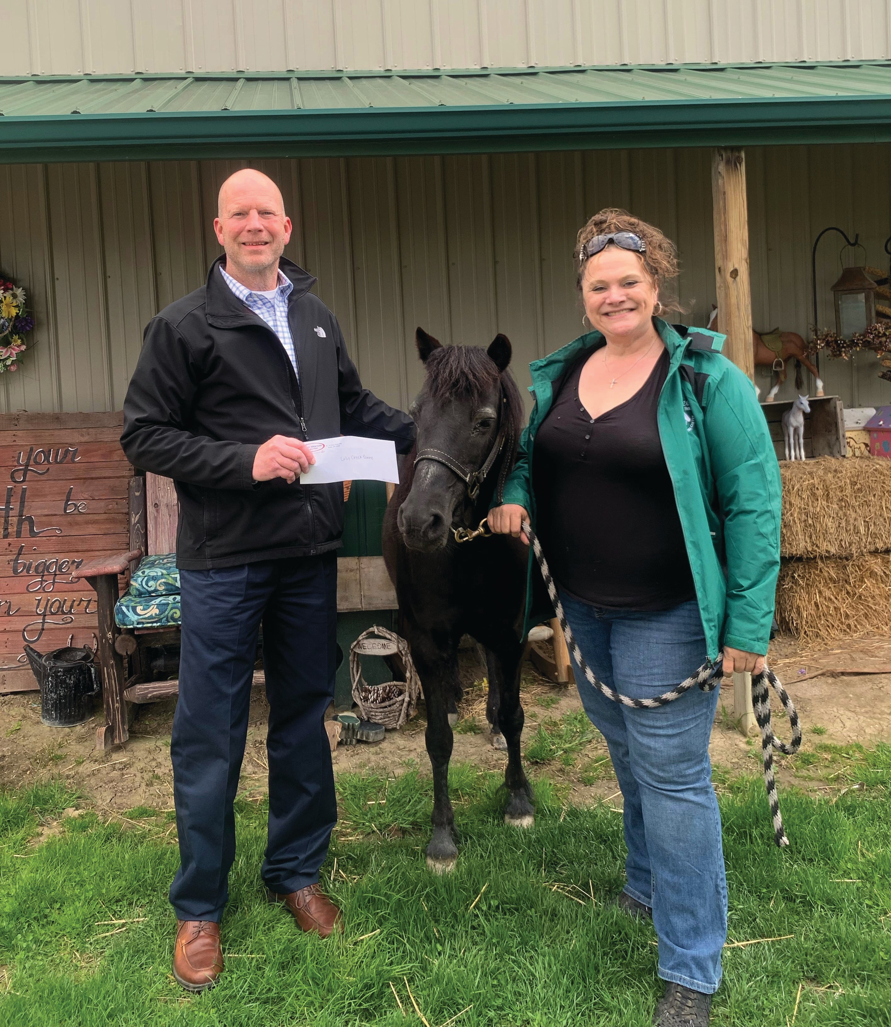 MAN HOLDING CHECK AND WOMAN HOLDING THE BRIDLE OF A BLACK HORSE