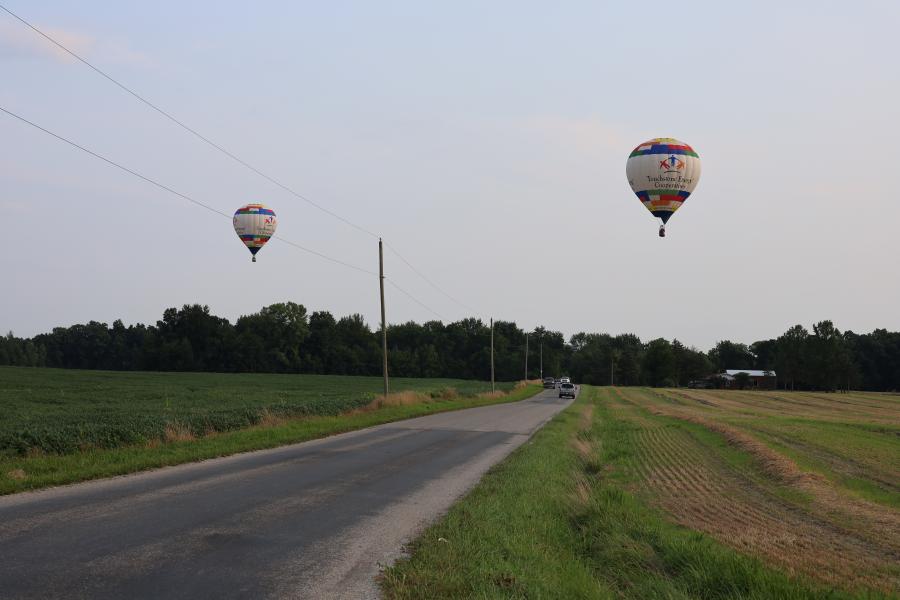 two balloons flying over country road