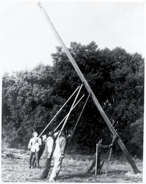 Linemen raising electric pole by hand