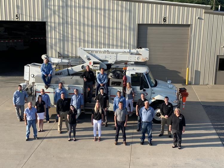Employees standing beside bucket truck